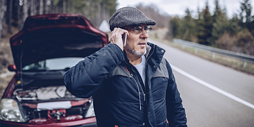 Man calling for help in front of his broken-down car.