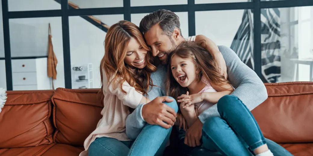 Family of three laughing on sofa